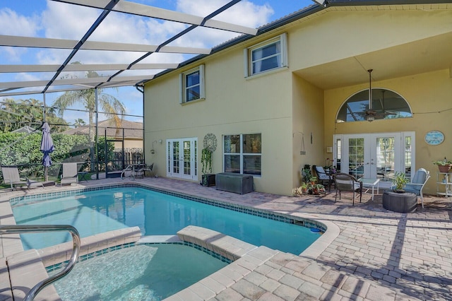 view of pool with a lanai, a patio area, a pool with connected hot tub, and french doors