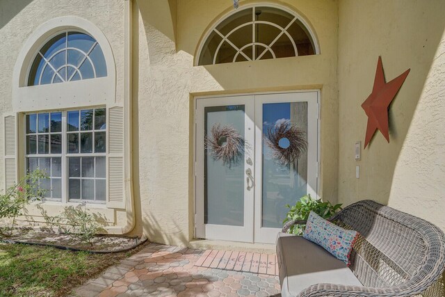 property entrance with stucco siding and french doors