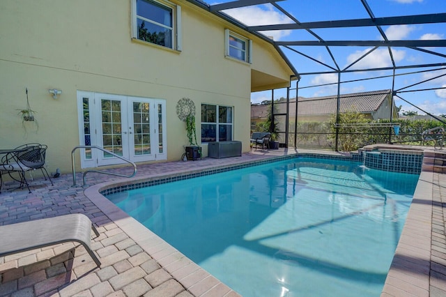 view of swimming pool featuring a pool with connected hot tub, french doors, a patio, and a lanai