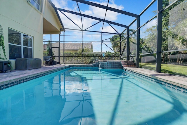 view of pool featuring glass enclosure, a pool with connected hot tub, and a patio area