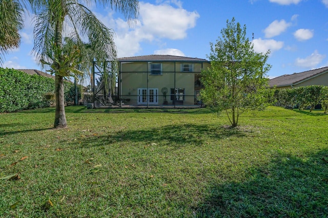 rear view of property featuring a lanai, a yard, and stucco siding