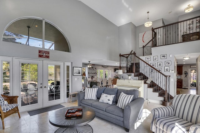 living area with french doors, baseboards, stairway, and a high ceiling