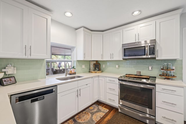 kitchen featuring stainless steel appliances, dark wood-type flooring, a sink, white cabinets, and light countertops