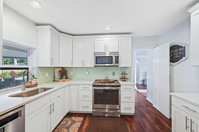 kitchen featuring stainless steel appliances, a sink, white cabinets, light countertops, and dark wood finished floors