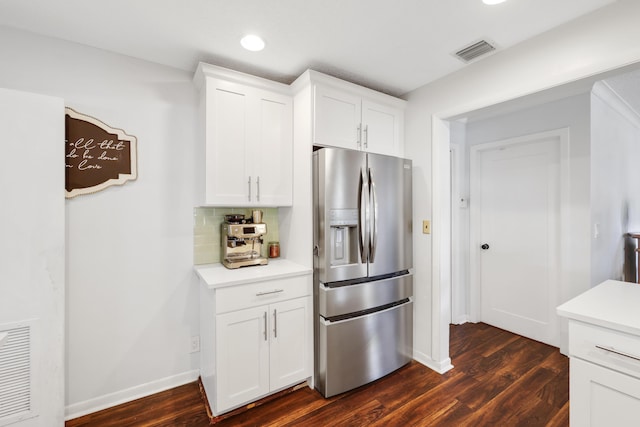 kitchen with light countertops, visible vents, backsplash, white cabinets, and stainless steel fridge