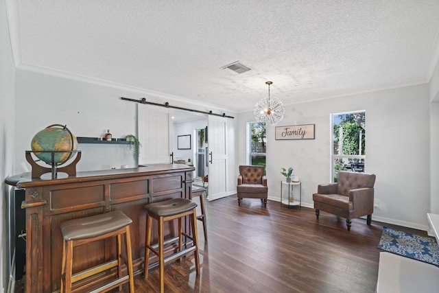 interior space with a barn door, visible vents, ornamental molding, dark wood-style flooring, and a textured ceiling