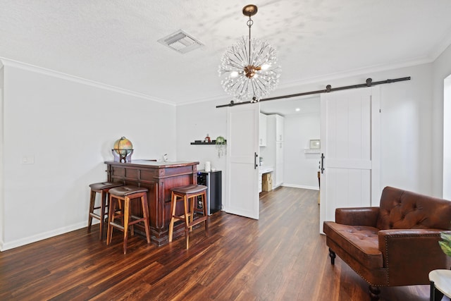 bar featuring a barn door, dark wood-style flooring, visible vents, baseboards, and crown molding