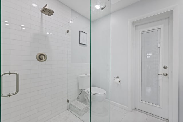 full bathroom with tiled shower, toilet, and tile patterned floors