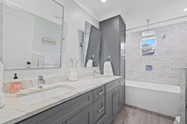 full bathroom featuring a freestanding tub, double vanity, a sink, and wood finished floors