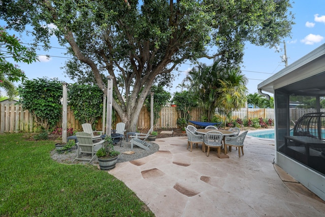 view of patio / terrace featuring a fenced in pool, outdoor dining area, a fenced backyard, and a sunroom