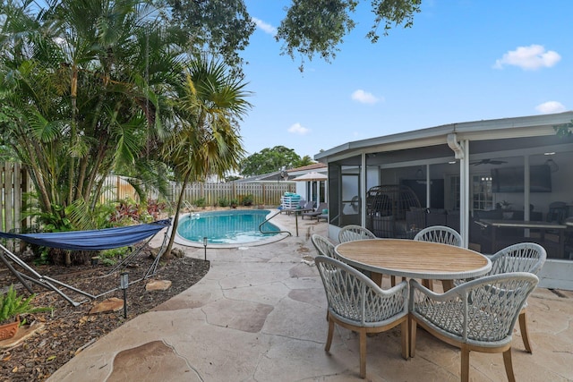 view of swimming pool with a fenced in pool, outdoor dining area, a sunroom, a patio area, and a fenced backyard