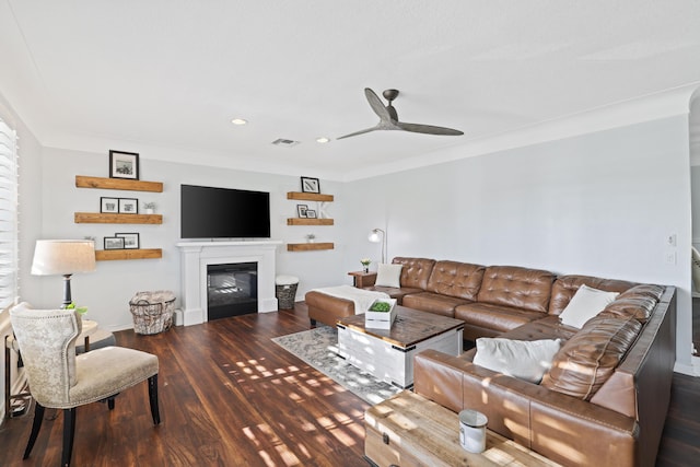 living room featuring visible vents, a glass covered fireplace, dark wood-style floors, ceiling fan, and crown molding