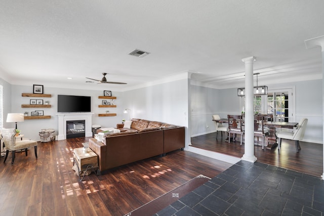 living area featuring dark wood-style flooring, visible vents, and decorative columns