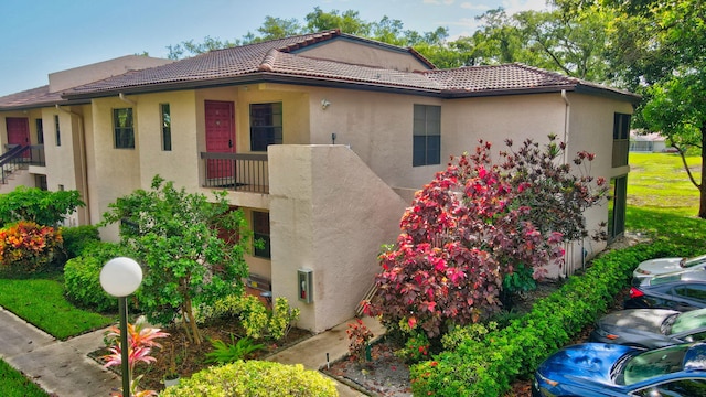 view of front of property featuring a balcony, stucco siding, and a tiled roof