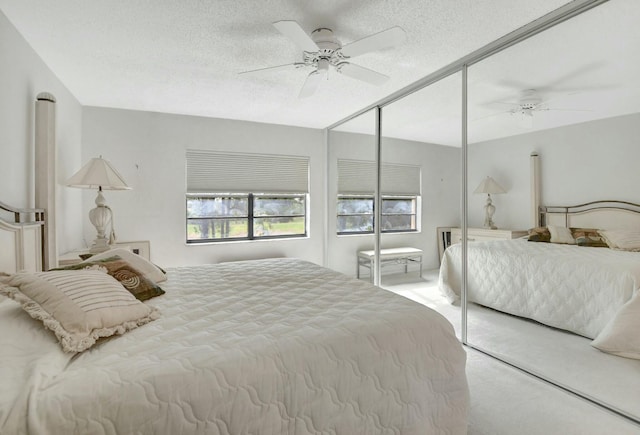 bedroom featuring a textured ceiling, ceiling fan, a closet, and light colored carpet