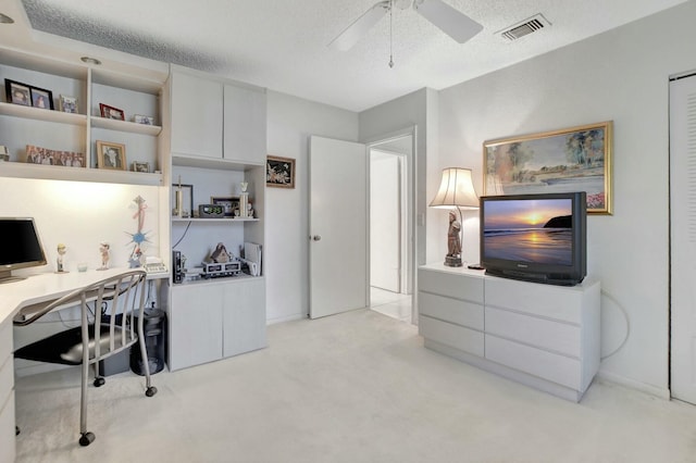 office area with ceiling fan, visible vents, a textured ceiling, and light colored carpet