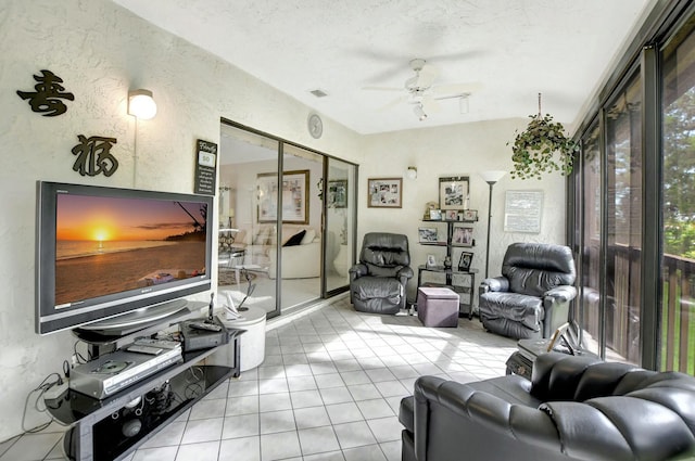 living area featuring light tile patterned floors, visible vents, a textured wall, a ceiling fan, and a textured ceiling