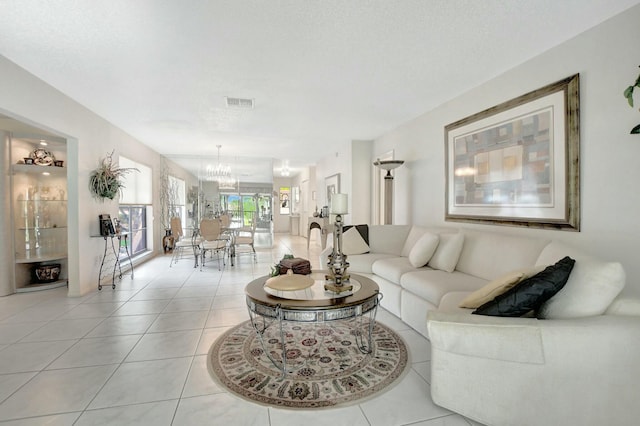 living area with light tile patterned floors, visible vents, a textured ceiling, and an inviting chandelier