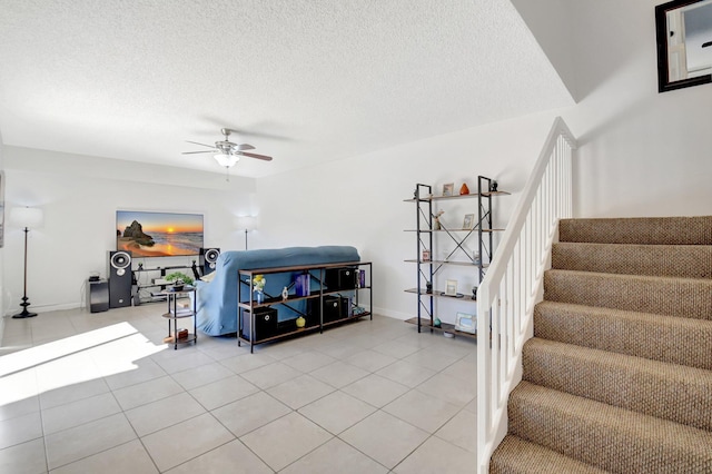 staircase with a textured ceiling, a ceiling fan, and tile patterned floors