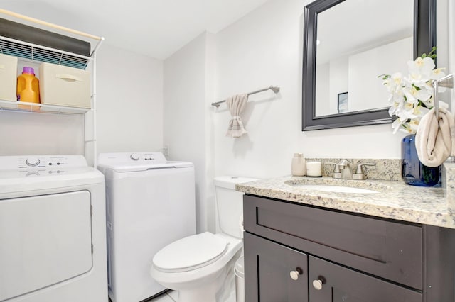 half bathroom featuring washing machine and clothes dryer, toilet, and vanity