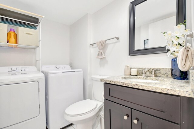 bathroom with independent washer and dryer, vanity, and toilet