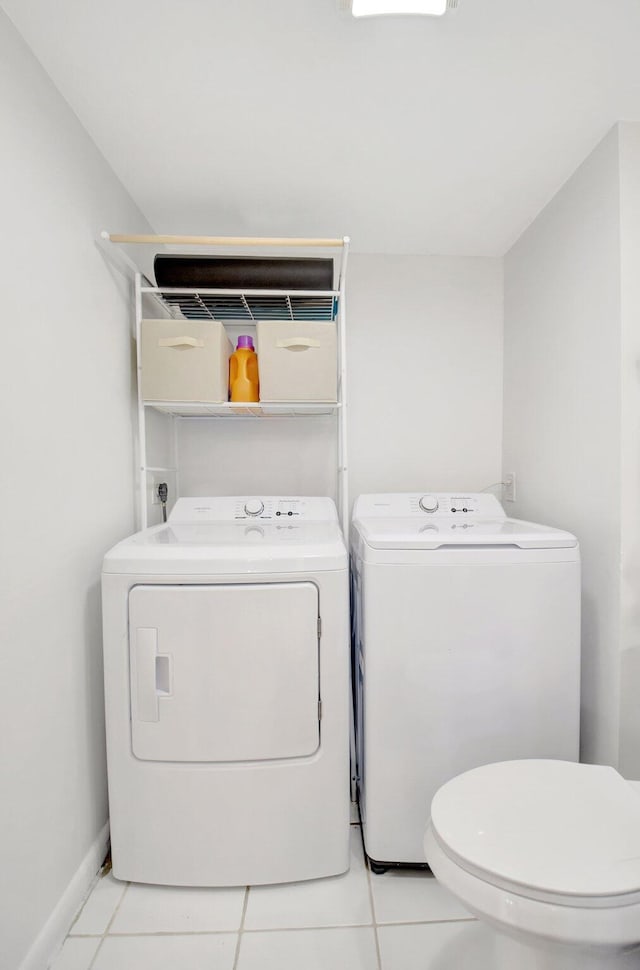 washroom with laundry area, light tile patterned floors, baseboards, and washing machine and clothes dryer
