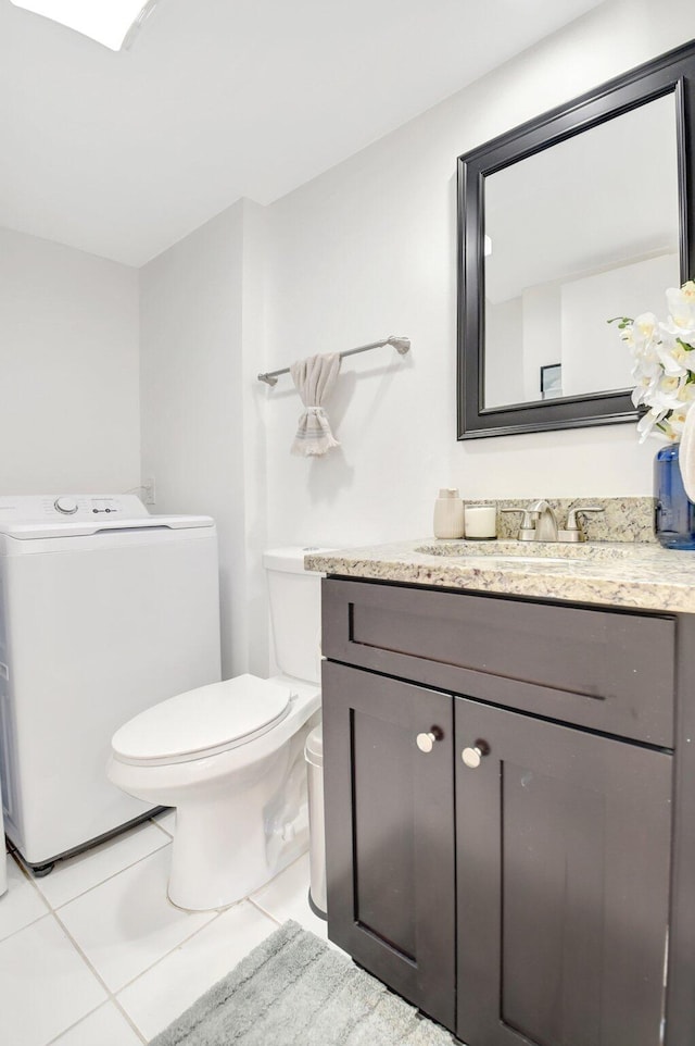 half bathroom with washer / clothes dryer, vanity, toilet, and tile patterned floors