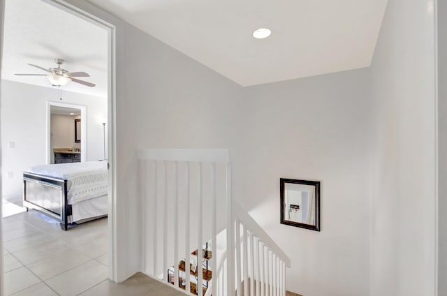 hall featuring light tile patterned floors and an upstairs landing