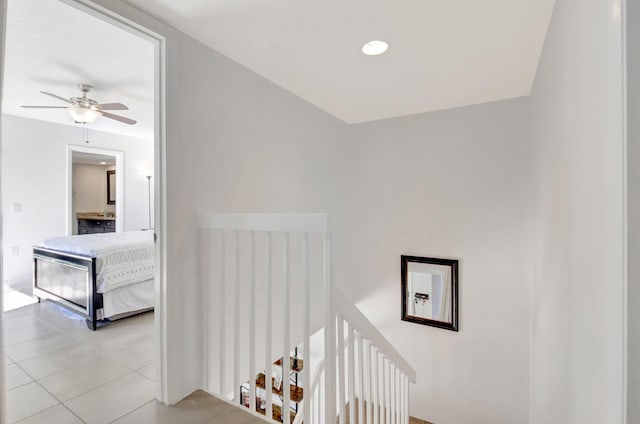 hall featuring light tile patterned flooring and an upstairs landing