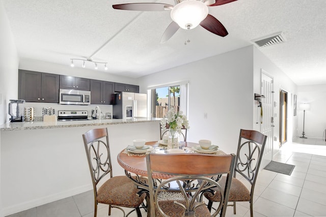 dining area featuring light tile patterned floors, ceiling fan, visible vents, and a textured ceiling