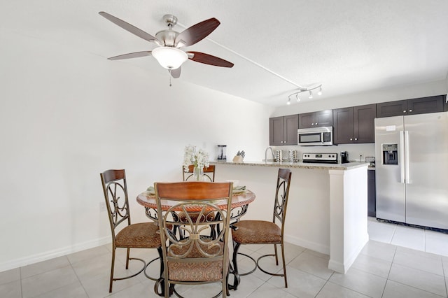 dining space with light tile patterned floors, baseboards, rail lighting, and ceiling fan