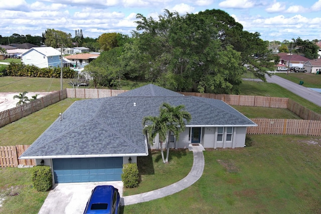 view of front of house with an attached garage, fence private yard, a shingled roof, concrete driveway, and a front yard