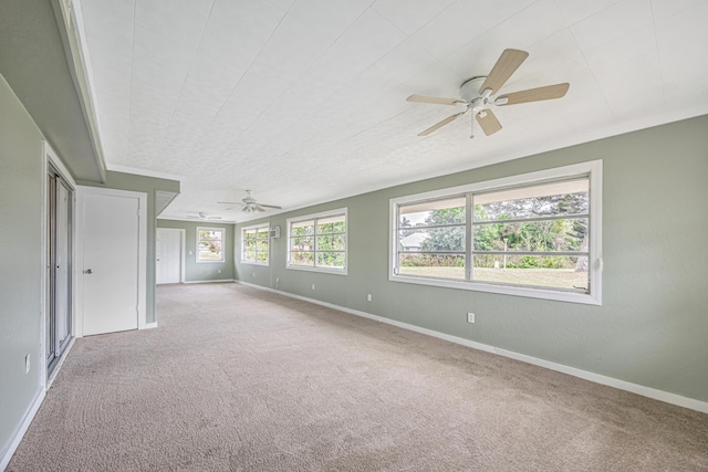 empty room with baseboards, a ceiling fan, and light colored carpet