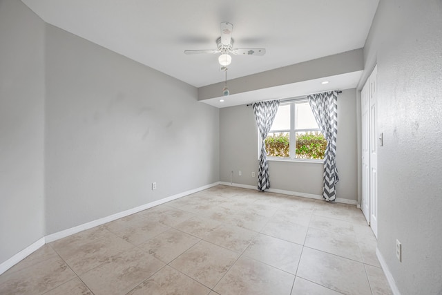 spare room with light tile patterned floors, baseboards, and a ceiling fan