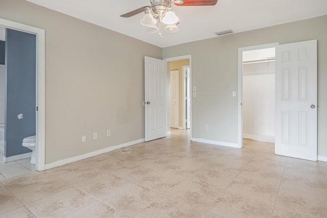 unfurnished bedroom with ensuite bathroom, light tile patterned floors, visible vents, baseboards, and a spacious closet