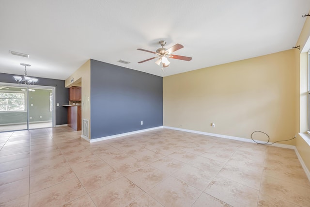 empty room featuring light tile patterned floors, baseboards, visible vents, and ceiling fan with notable chandelier