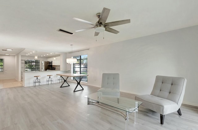 unfurnished room featuring ceiling fan with notable chandelier, light wood-type flooring, visible vents, and baseboards