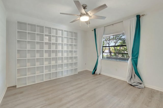 empty room featuring light wood-type flooring, baseboards, and a ceiling fan