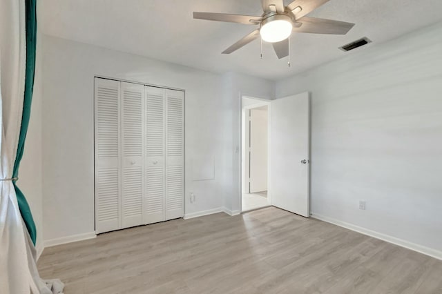 unfurnished bedroom featuring baseboards, visible vents, a ceiling fan, light wood-type flooring, and a closet