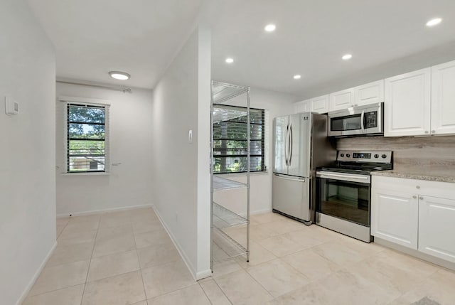 kitchen with tasteful backsplash, white cabinets, light stone countertops, stainless steel appliances, and recessed lighting