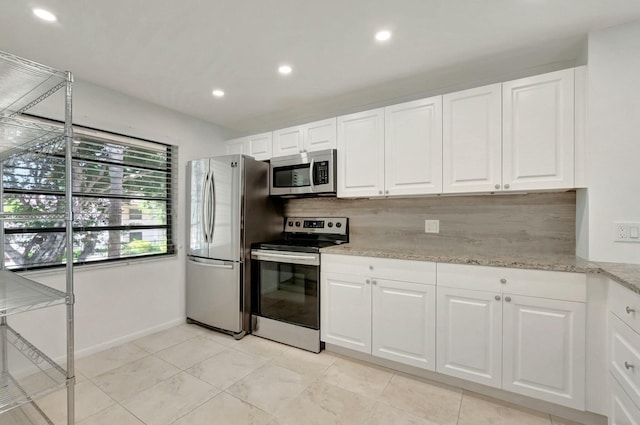 kitchen with tasteful backsplash, white cabinets, appliances with stainless steel finishes, light stone countertops, and recessed lighting