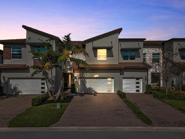 view of front of property featuring an attached garage, decorative driveway, and stucco siding