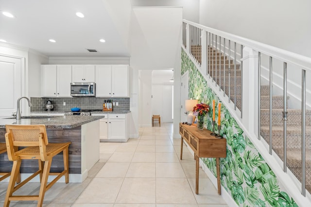 kitchen featuring visible vents, white cabinets, ornamental molding, tasteful backsplash, and stainless steel microwave