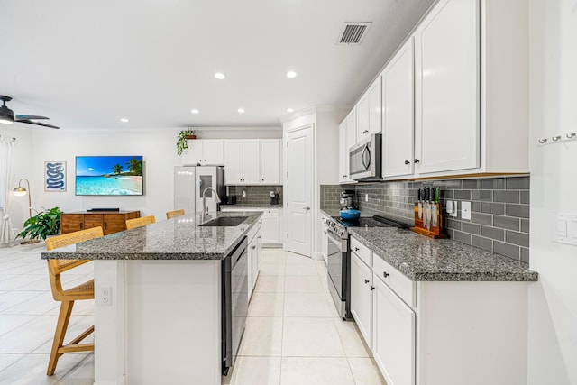 kitchen featuring white cabinetry, stainless steel appliances, and dark stone countertops