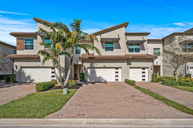 view of front of property with an attached garage, decorative driveway, and stucco siding