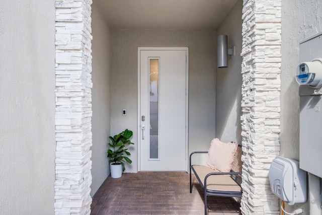 doorway to property with stone siding and stucco siding