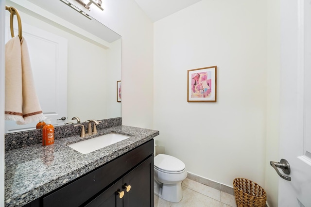 bathroom with toilet, vanity, baseboards, and tile patterned floors