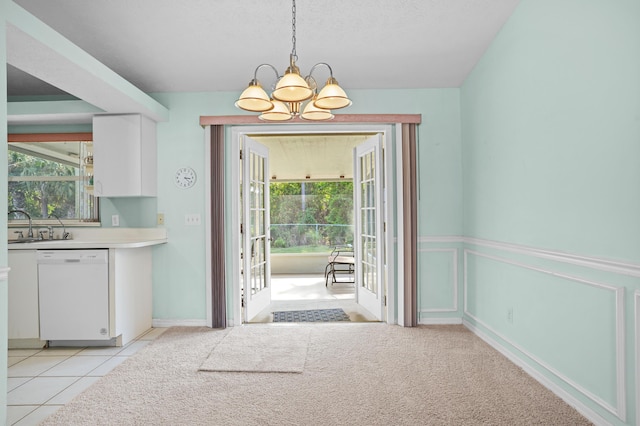 doorway to outside with a chandelier, light tile patterned flooring, light colored carpet, a sink, and wainscoting