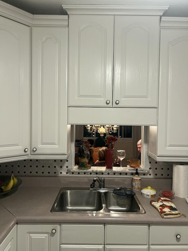 kitchen with tasteful backsplash, a sink, and white cabinets