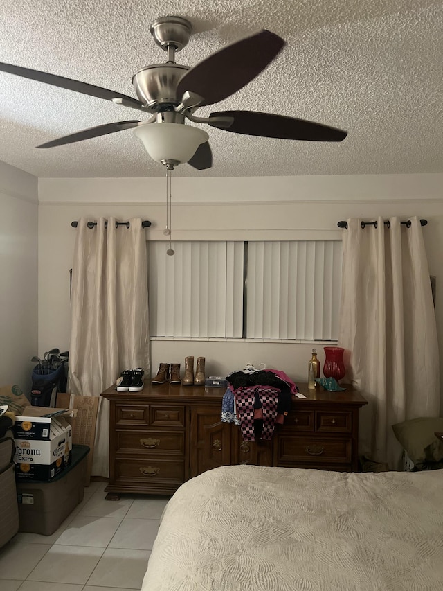 bedroom featuring ceiling fan, a textured ceiling, and light tile patterned floors